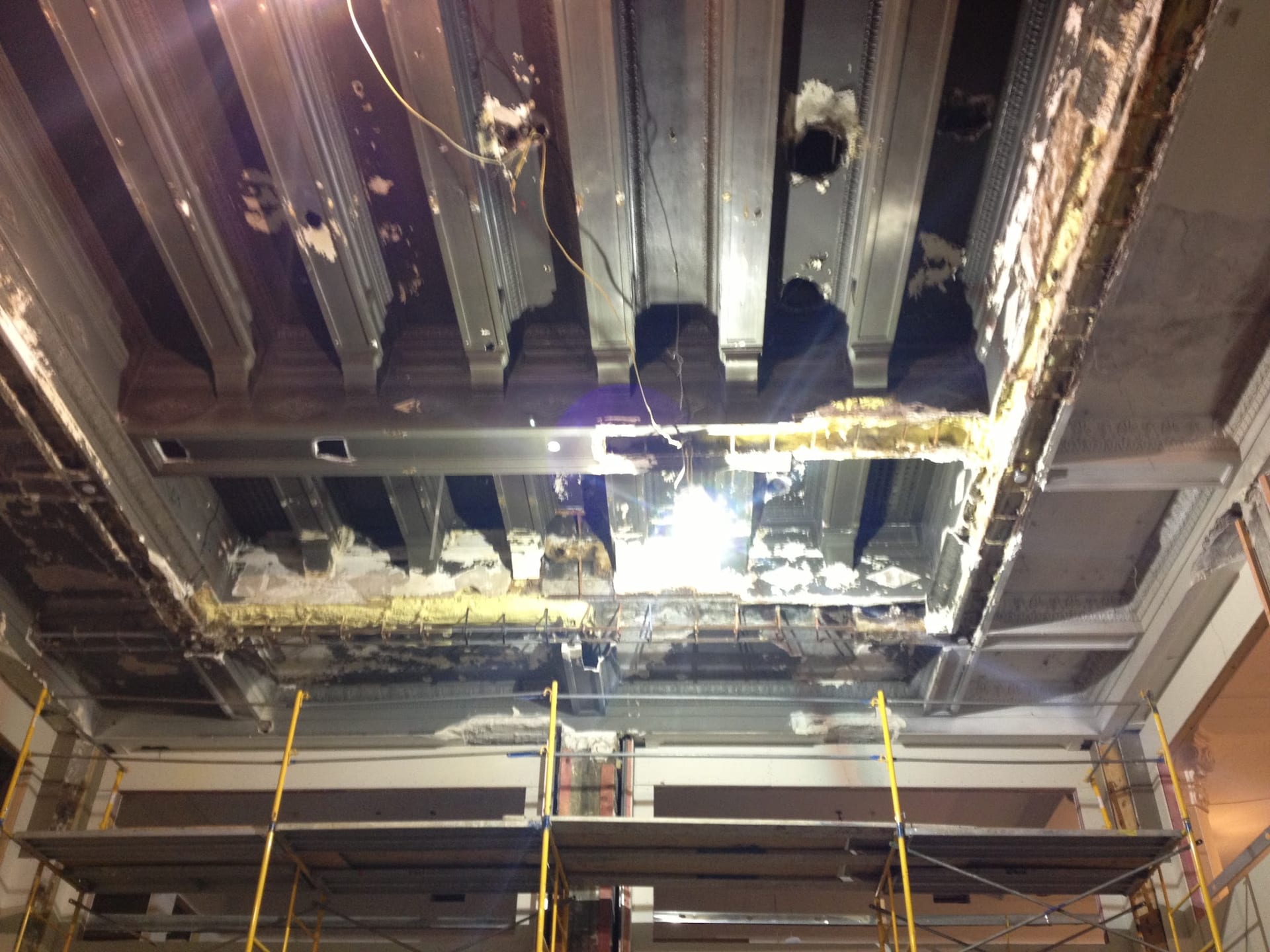 Commercial ceiling under renovation with exposed steel framing and scaffolding below