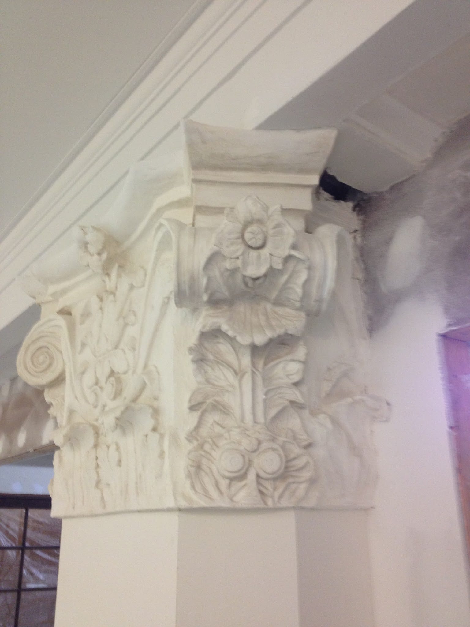 Ornate white decorative plaster column capital with floral and scroll details