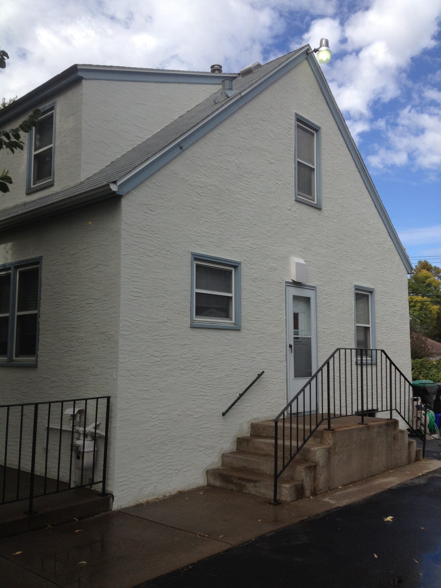 White textured stucco exterior on two-story residential building with entry stairs.