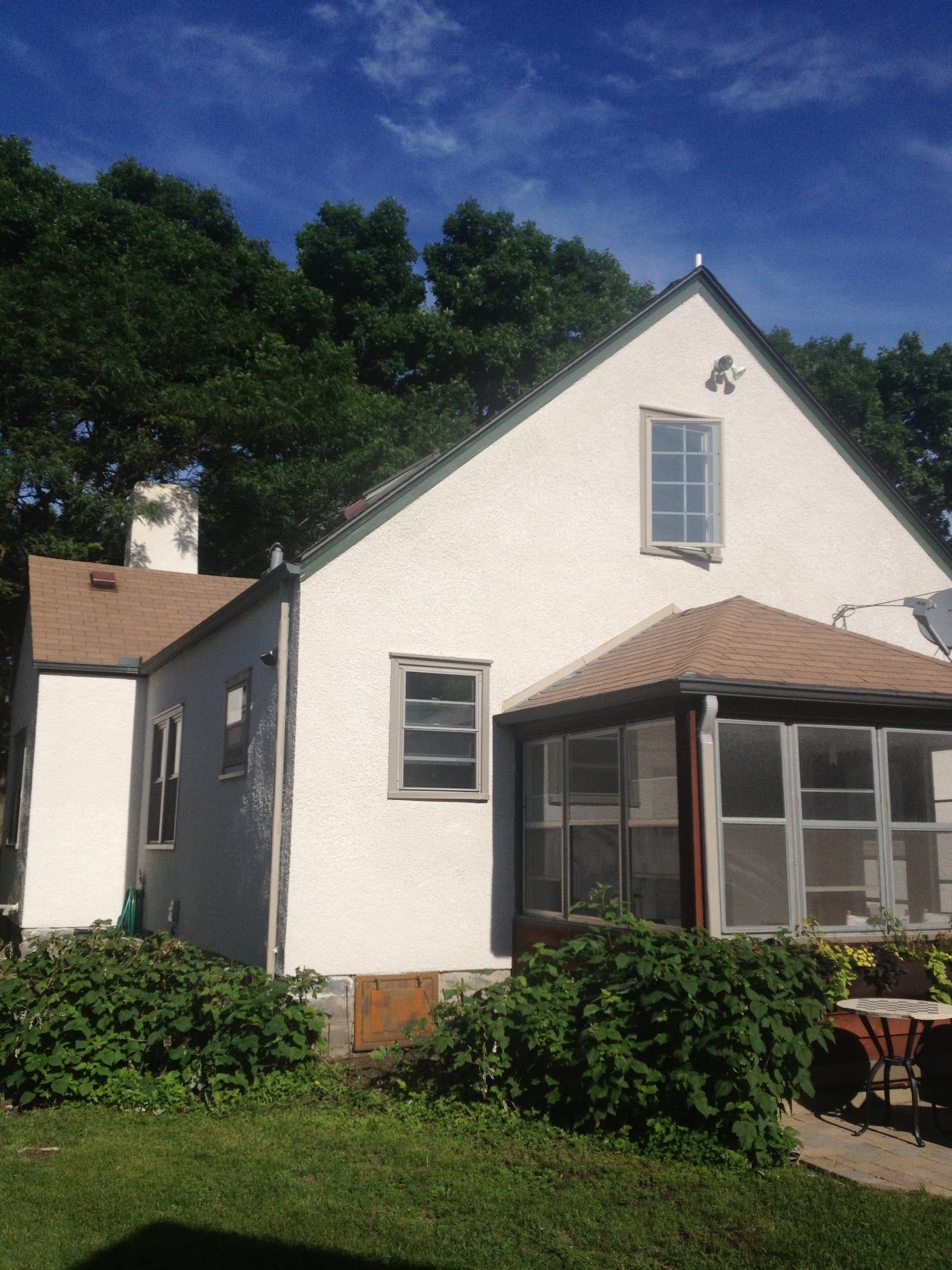 White stucco exterior on residential home with screened porch addition