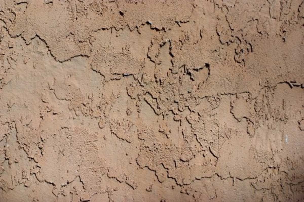Close-up of cracked and weathered hard coat stucco wall surface.