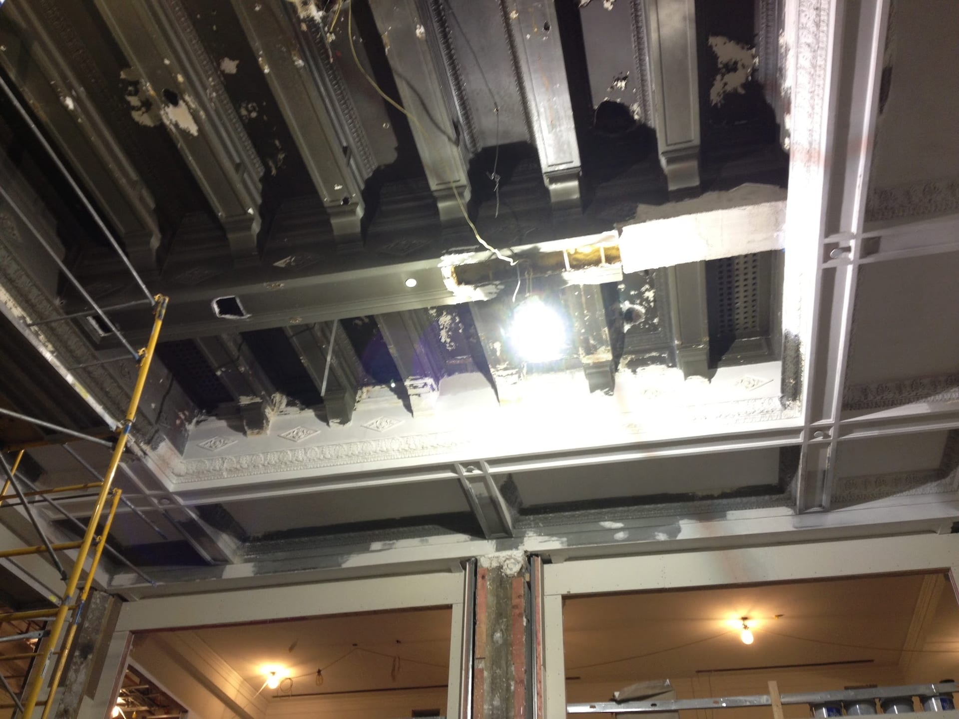 Historic ornate plaster ceiling exposed during interior renovation with scaffolding