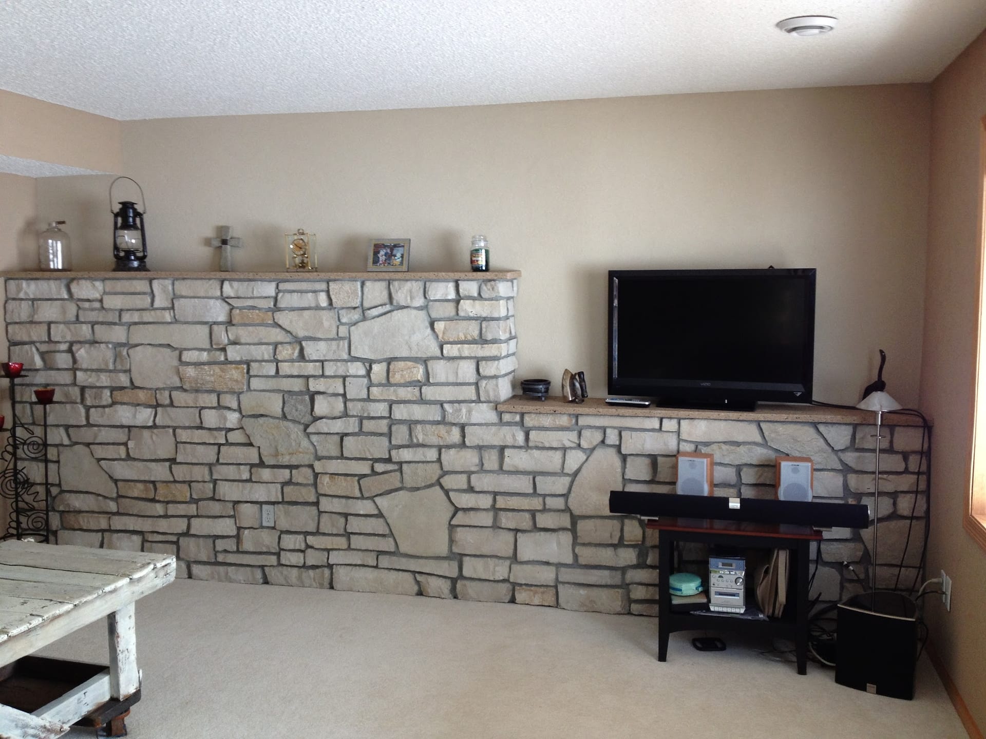 Stone accent wall with ledge shelf in finished basement living room