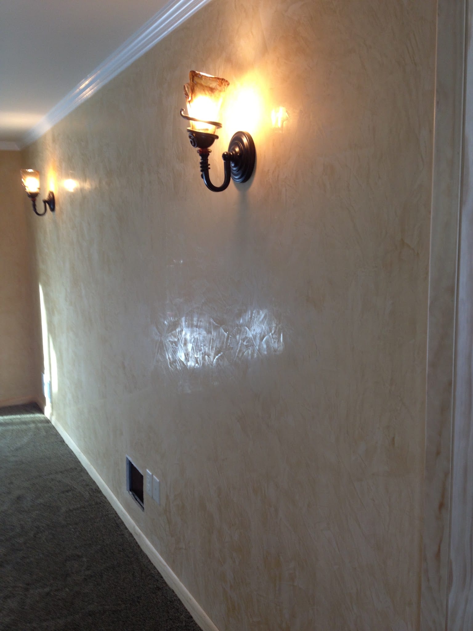 Smooth interior plaster wall finish in hallway with decorative wall sconces
