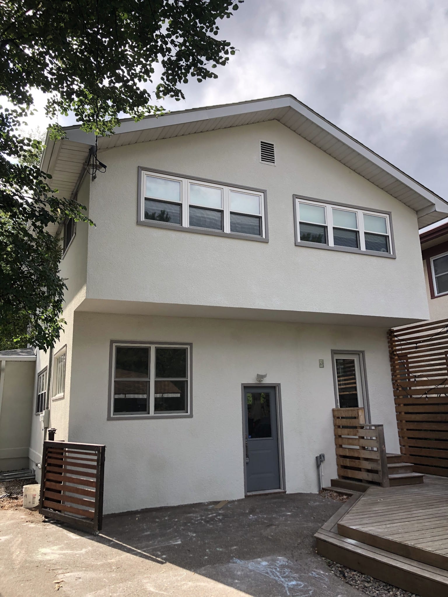 Two-story home with smooth white exterior stucco finish and wood deck.
