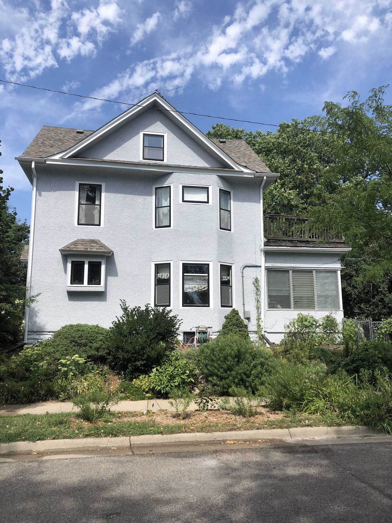 Two-story residential home with white exterior stucco finish and multiple windows.