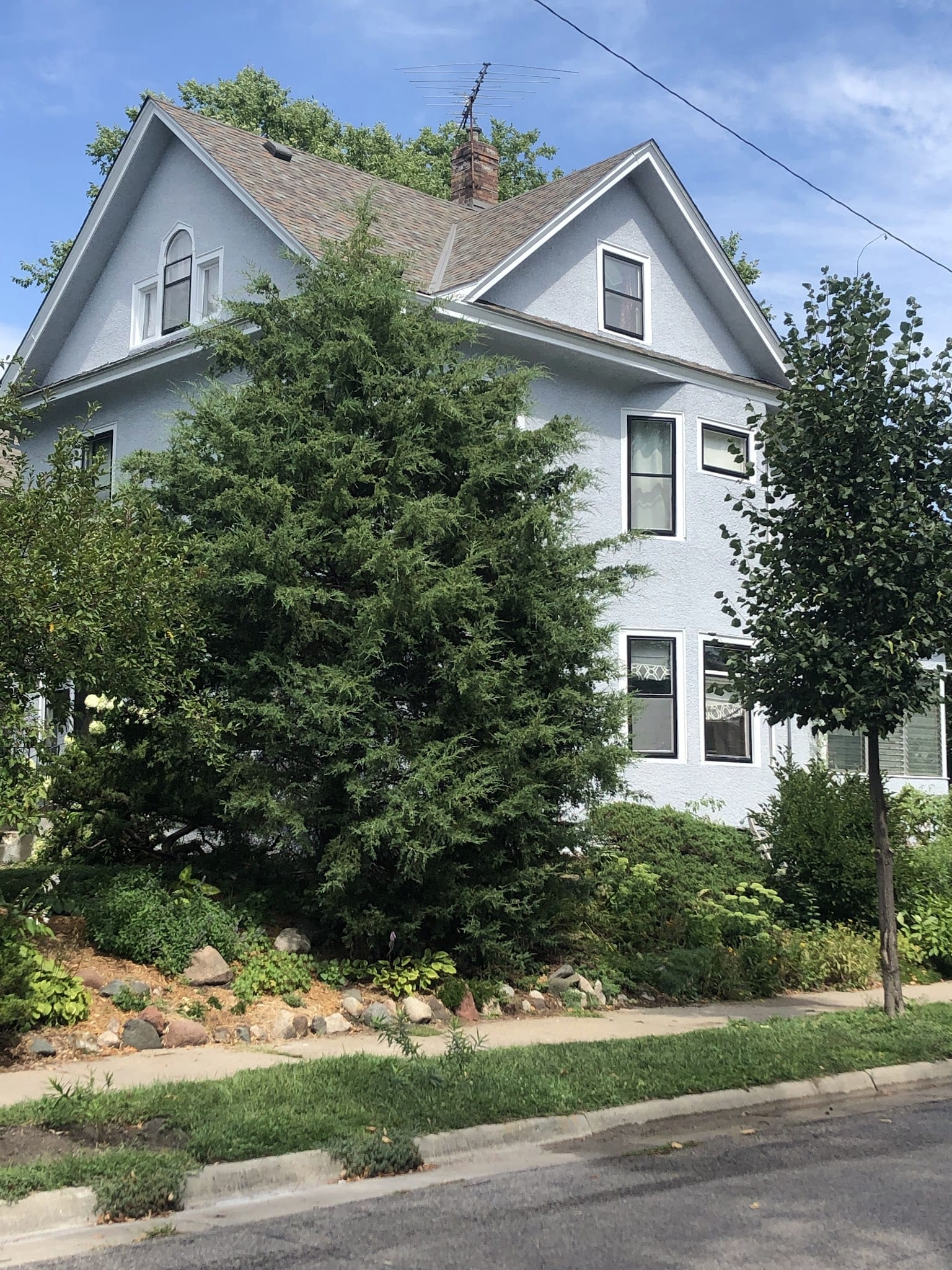 Light blue stucco exterior on a two-story residential home with mature trees