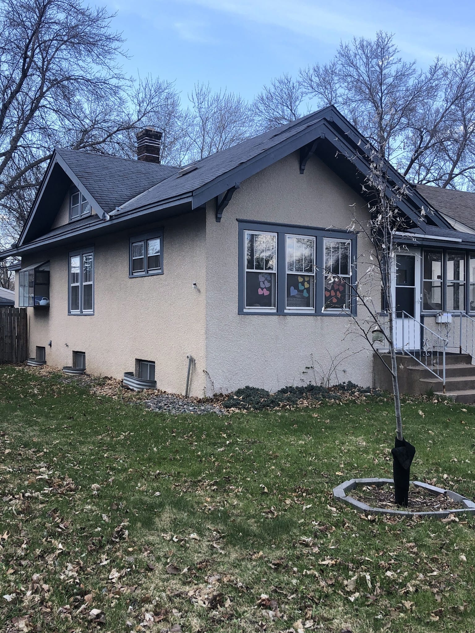 Craftsman bungalow with smooth stucco exterior and dark trim in late fall