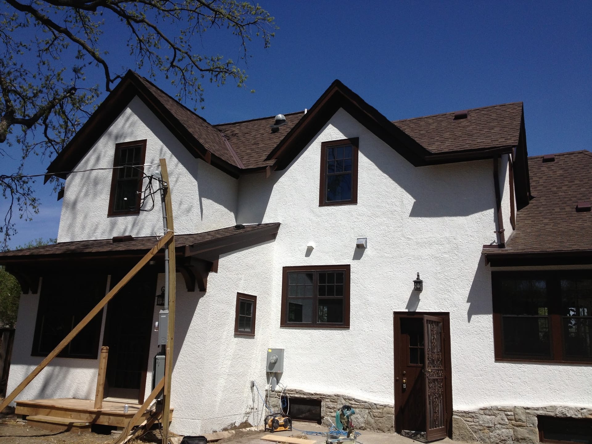 White residential stucco exterior with dark brown trim and multiple gables