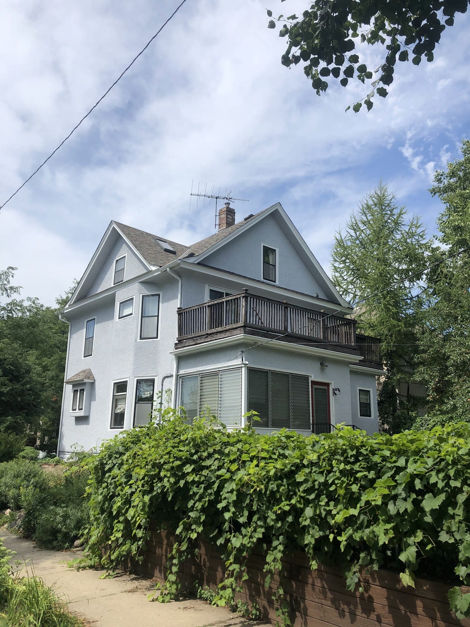 Two-story residential home with light gray exterior stucco finish and balcony.
