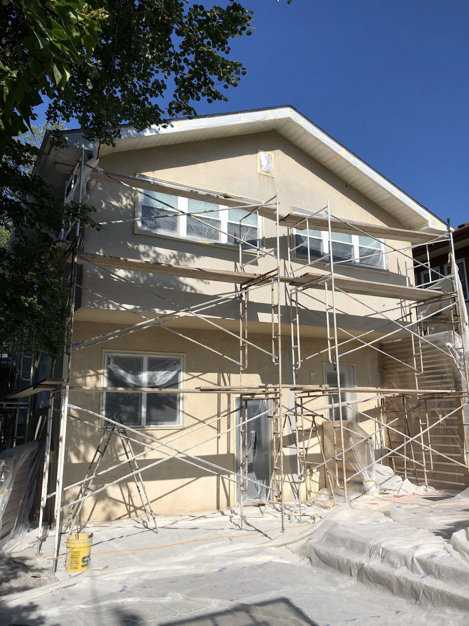 Two-story home with fresh stucco exterior and scaffolding during installation