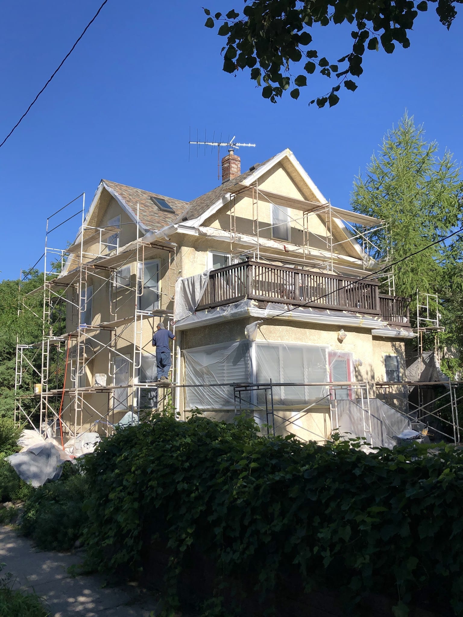 Worker on scaffolding applying stucco to two-story home exterior